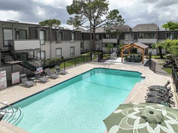 A swimming pool surrounded by a black fence and a gazebo in the middle of the pool.